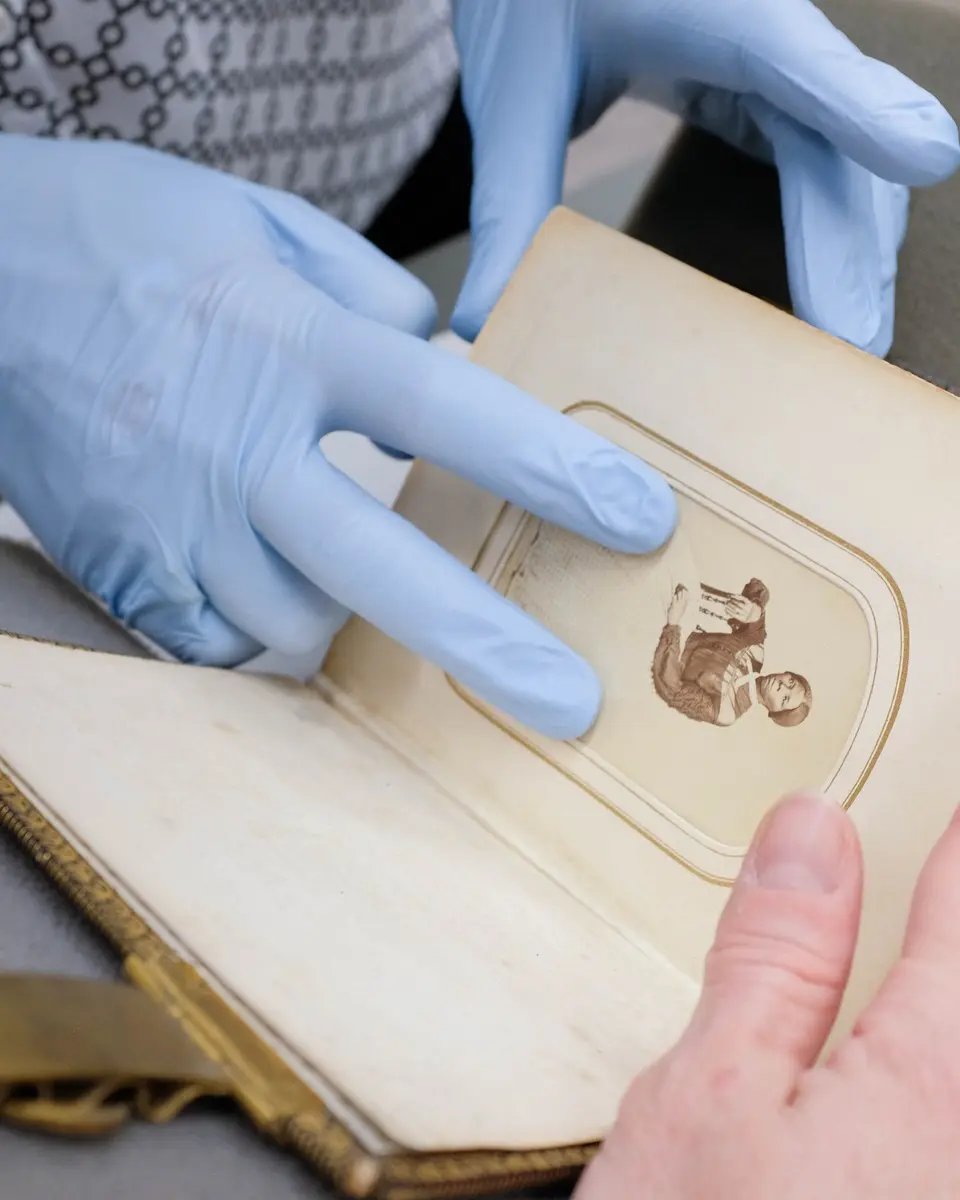 A conservator in gloves restoring a 19th-century photo album