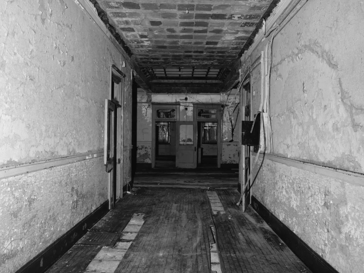 A worn hallway with cracked plaster walls in an older Akron school building