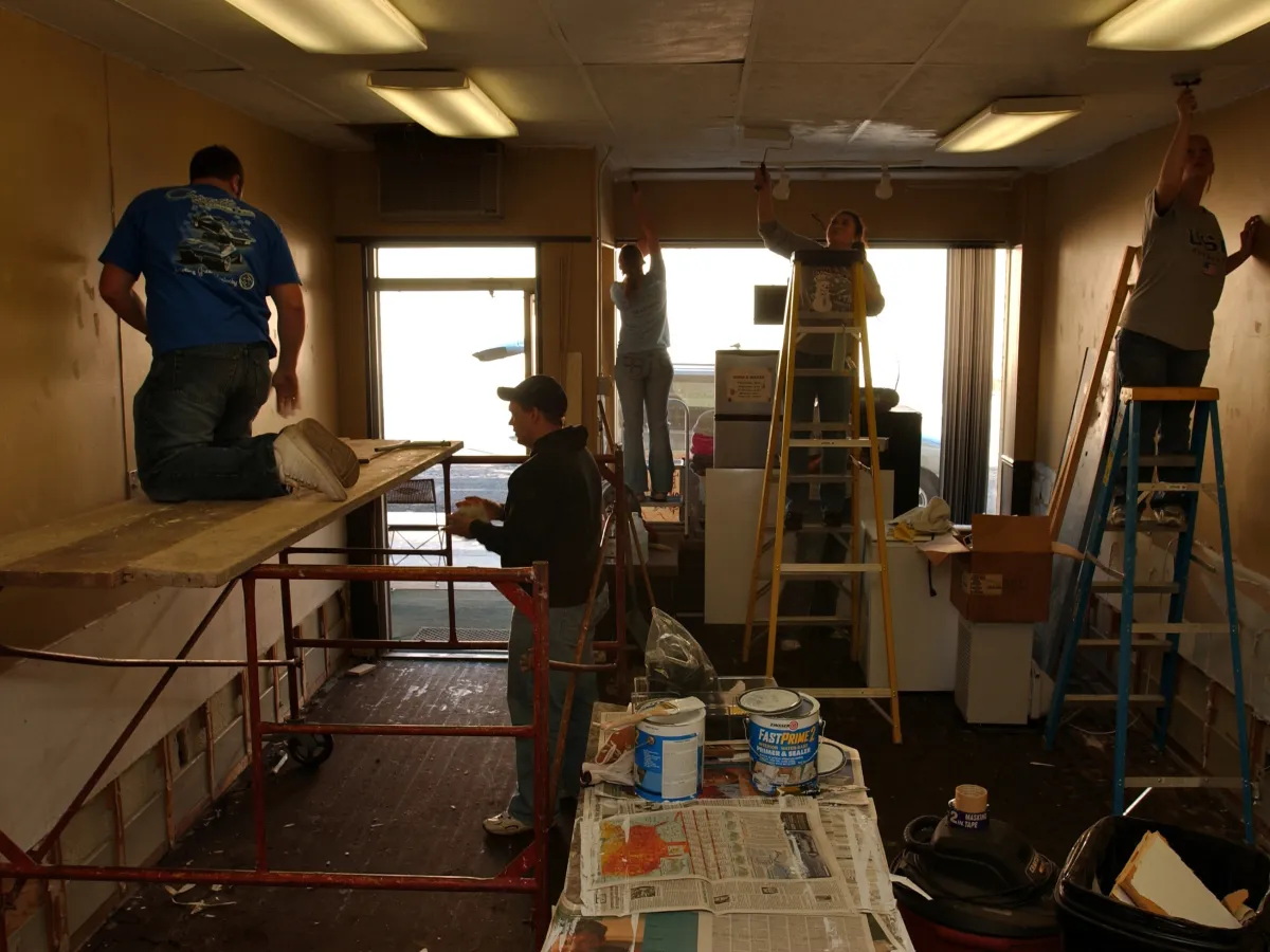 Volunteers on ladders and scaffolding repairing the walls of a flood-damaged Ohio business