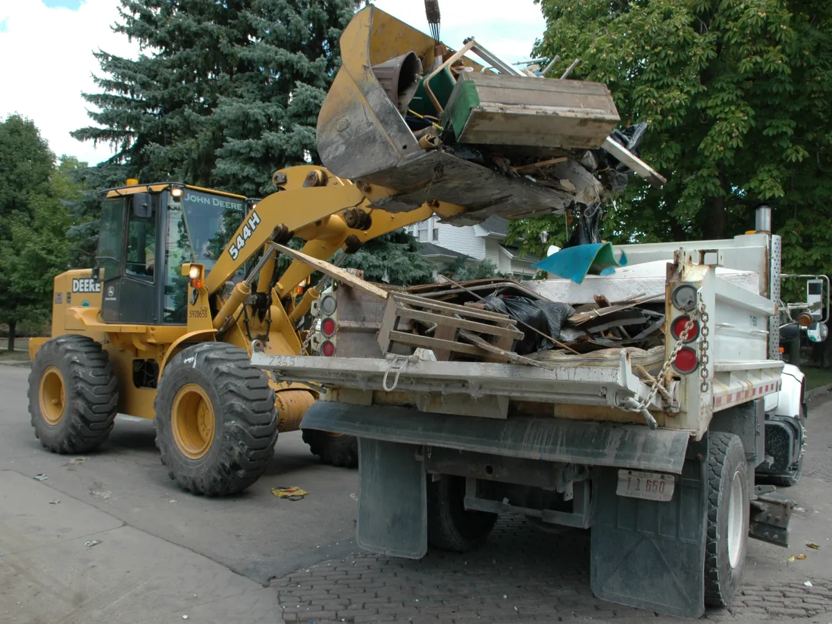 A loader dumping flood debris into a dump truck on an Ohio street