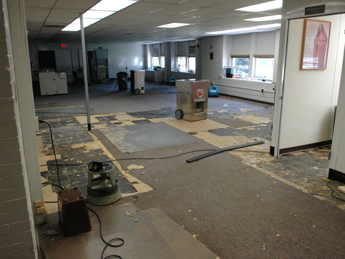 Dehumidifiers and air movers drying a room with its flooring pulled up