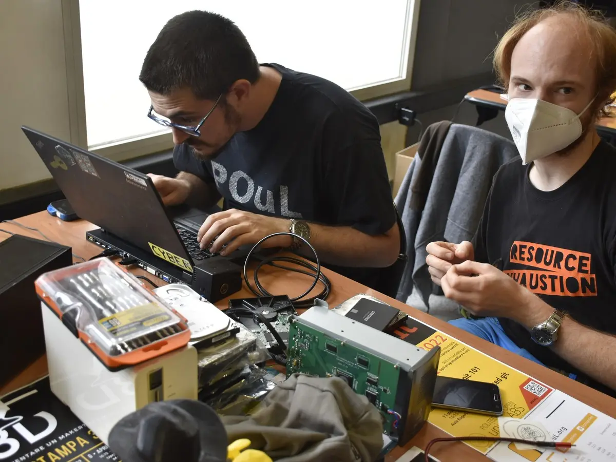 Technicians working on laptops with repair tools spread across the bench