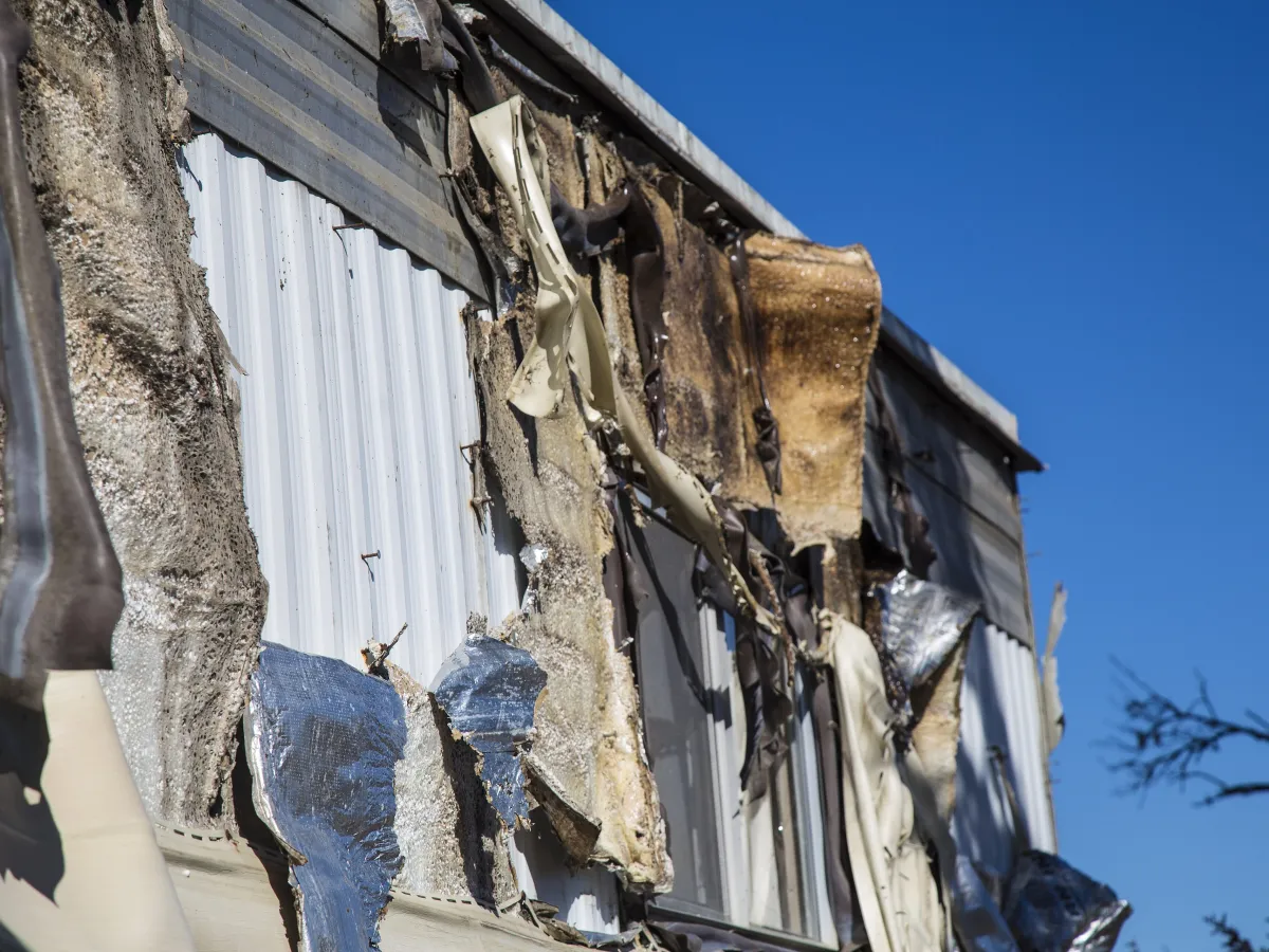 A fire-damaged house wall with exposed insulation