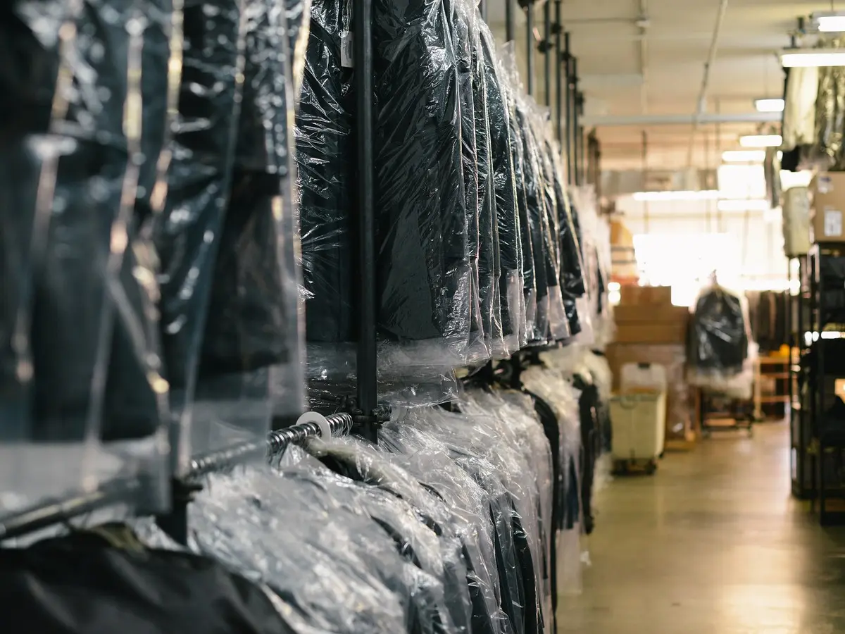 Freshly cleaned clothes hanging in plastic garment bags on a drycleaning rail