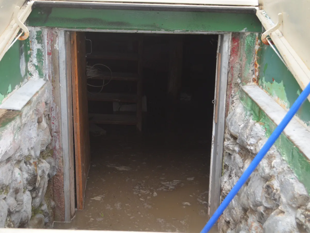 Muddy floodwater covering a basement floor, seen through the open cellar door