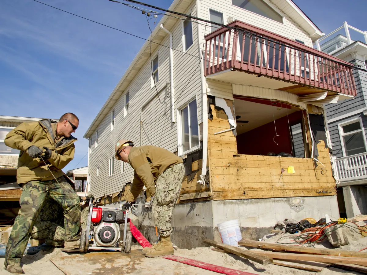 Two workers starting a pump to clear water from a flooded basement